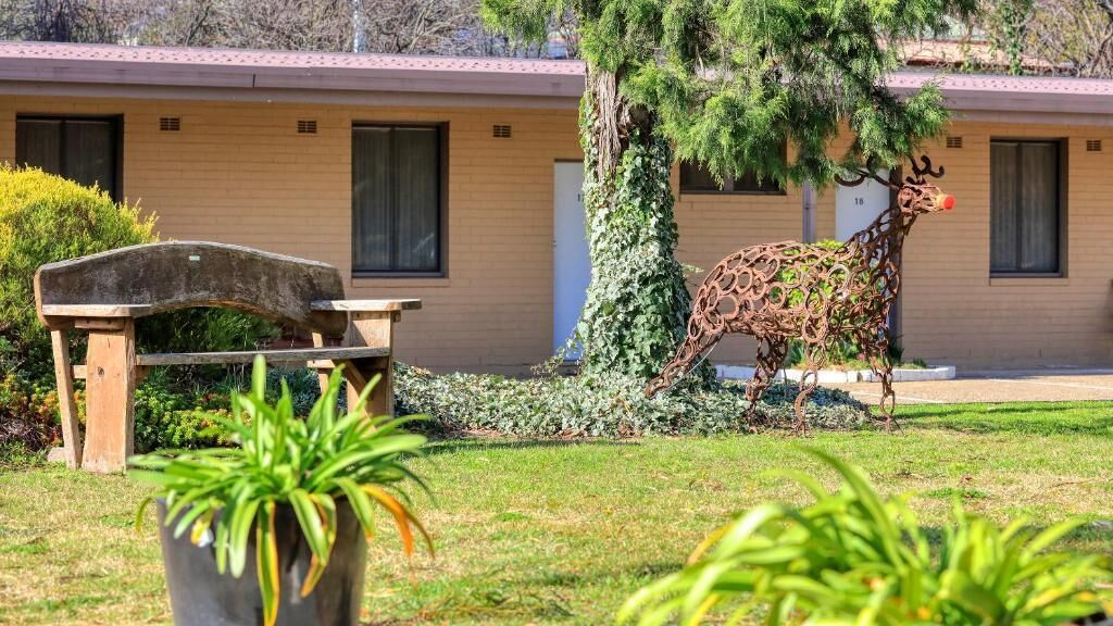 A building with a brick facade, a bench, and a metal reindeer sculpture.