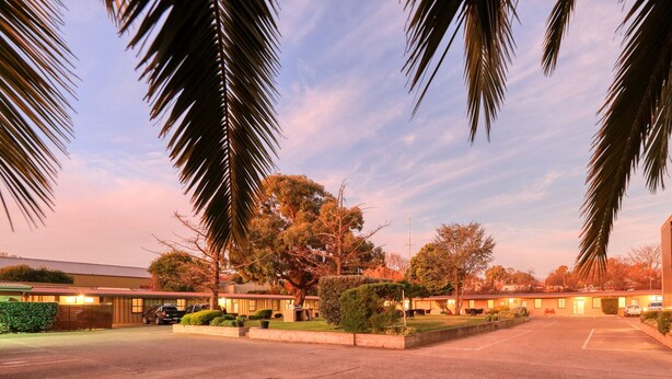 A hotel with a parking lot, multiple buildings, and palm trees.