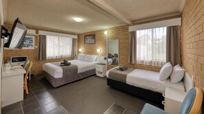 A hotel room with two beds, a desk with a computer, a microwave, and a dining area with chairs.