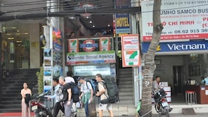Una entrada de hotel con varios letreros, incluyendo una tienda 7-Eleven, una pescadería de fish and chips y una agencia de viajes.