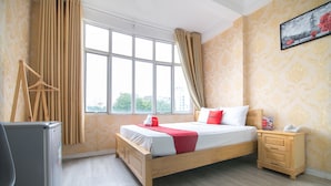 Una habitación de hotel con cama, mesita de noche, escritorio y ventana con cortinas.