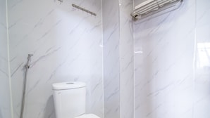 Un baño con inodoro, ducha y toallero.