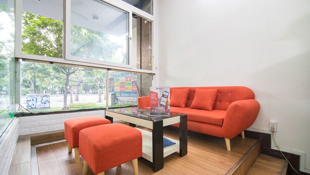 Una habitación moderna con una mesa de vidrio, un sofá rojo y otomanas a juego.