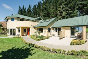 A two-story building with a green roof, a covered patio, and a landscaped garden.