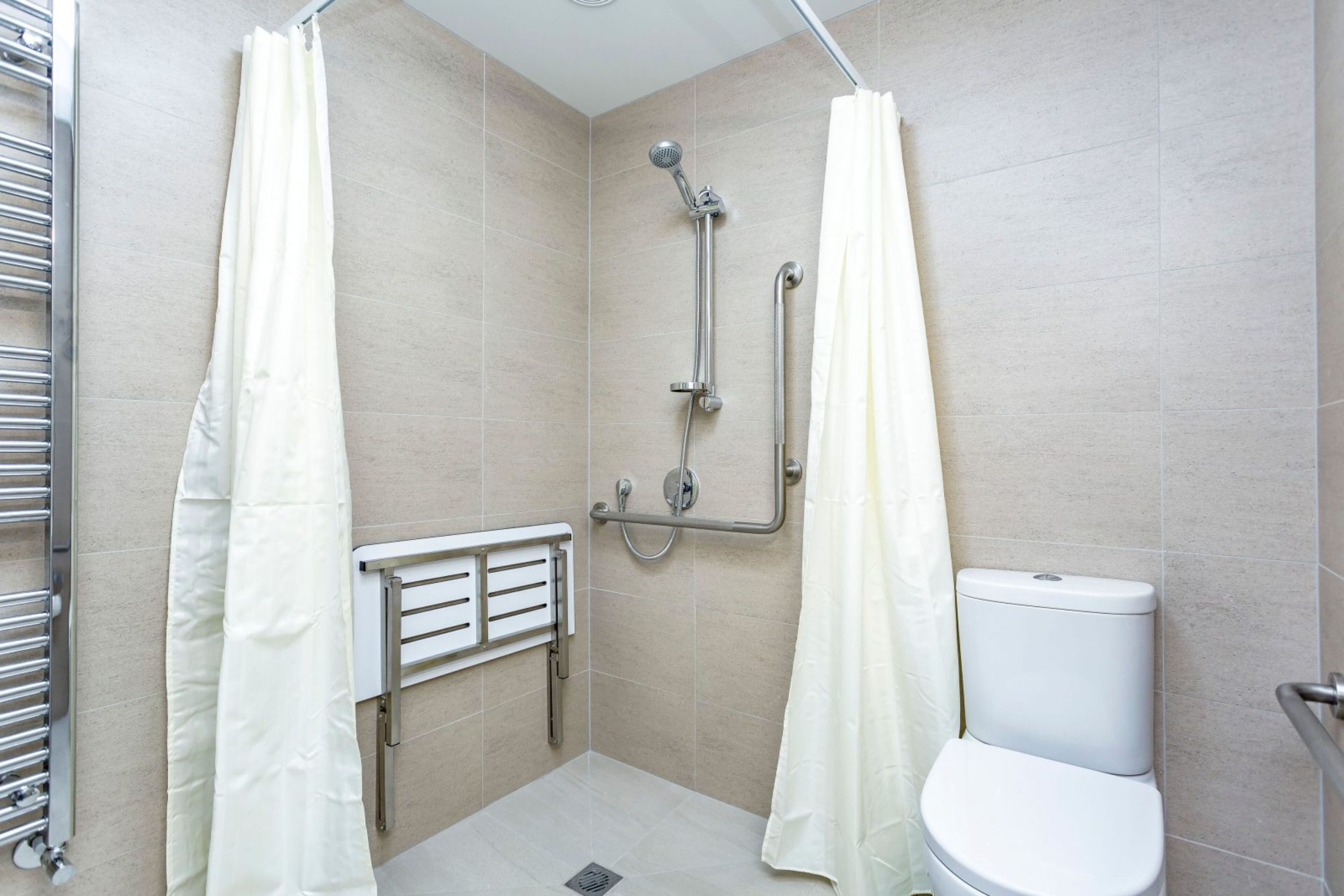 Ein kleines, modernes Badezimmer mit Dusche, Toilette und Haltestange.