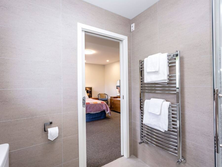 Et moderne badeværelse med bruser, håndklædetørrestativ og toilet.