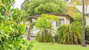A single-story house with a small front yard, surrounded by lush greenery and trees. - Biloela Countryman Motel (Biloela)