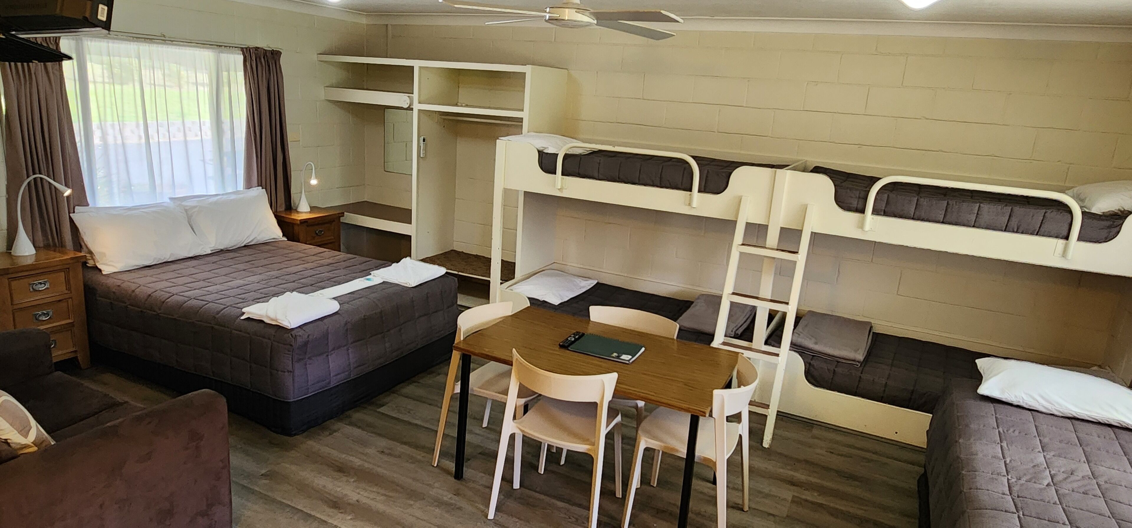 A compact room with bunk beds, a single bed, a desk with chairs, and a small table.