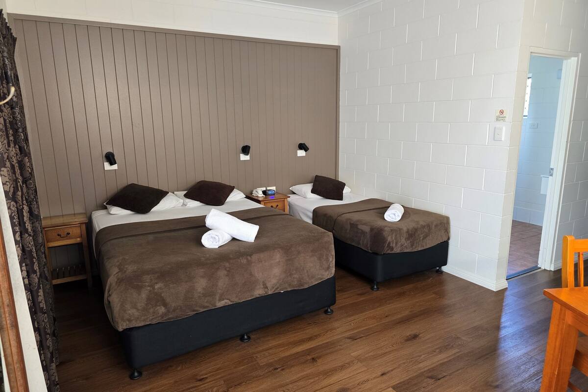 Ein Hotelzimmer mit zwei Betten, Holzboden und einer Wand aus weißen Ziegeln.