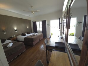 A hotel room with a bed, a sofa, a dining table, and a ceiling fan. - The Colonial Rose Motel (Mundingburra)