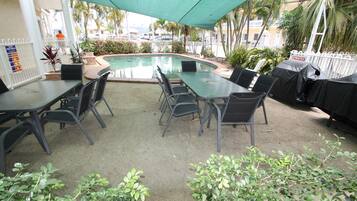 Ein Poolbereich im Freien mit überdachter Lounge-Bereich und Grillplatz.