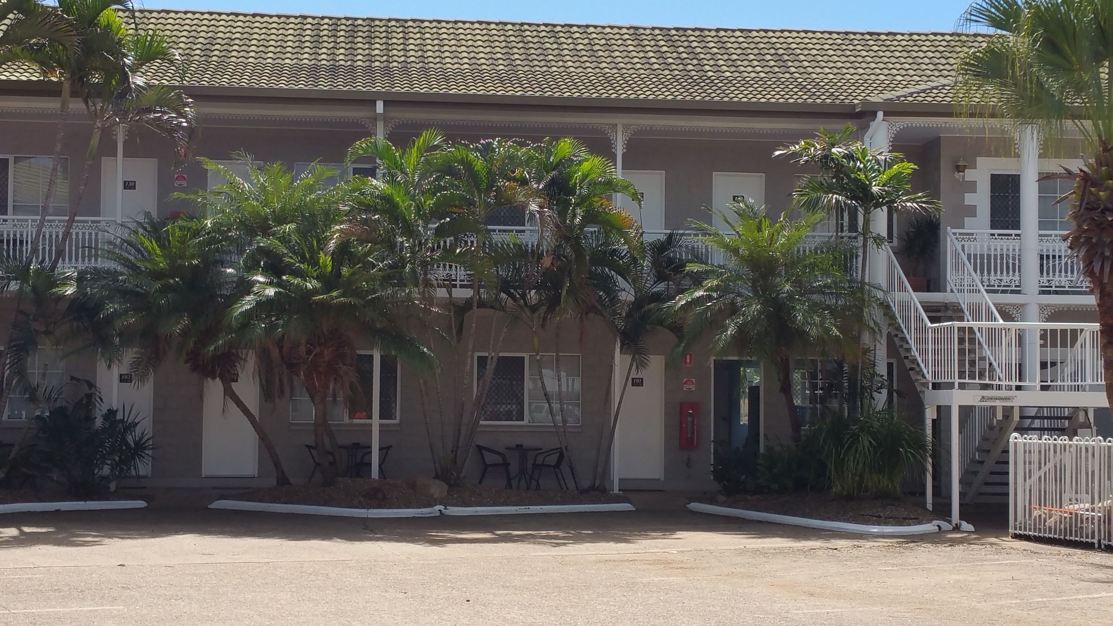Un edificio con tetto in tegole, palme e una scalinata.