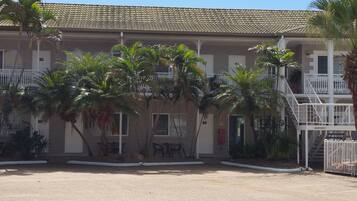 Un edificio con tetto in tegole, palme e una scalinata.