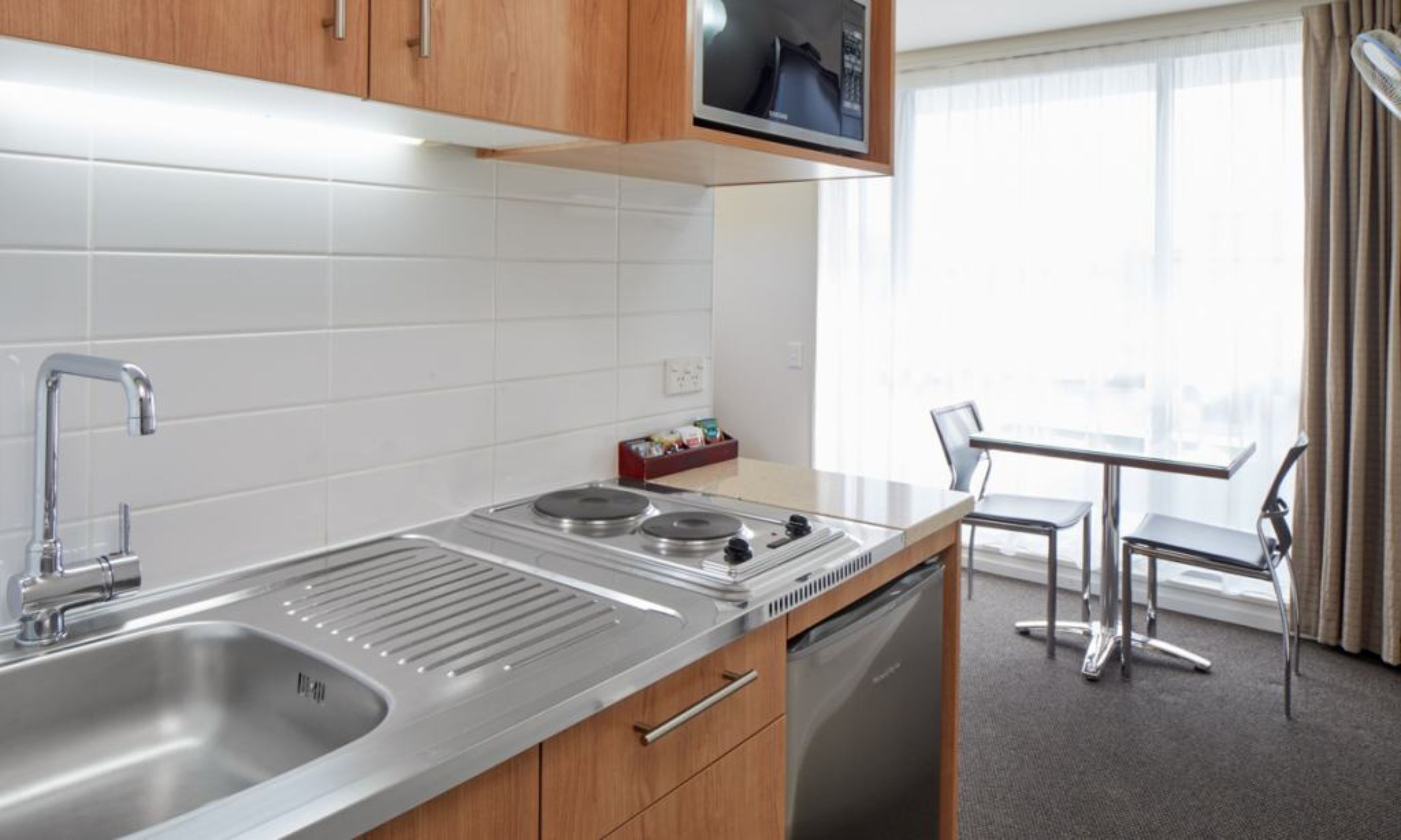 A modern kitchen with stainless steel appliances, a dishwasher, and a dining area with a table and chairs.