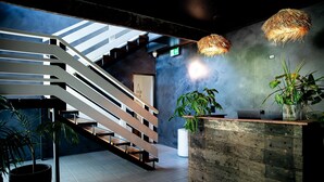 Un intérieur moderne avec un escalier, un comptoir d’accueil en bois et des plantes en pot.