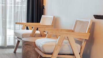 Una habitación moderna con dos sillas de madera, una mesita redonda y un televisor montado en la pared.