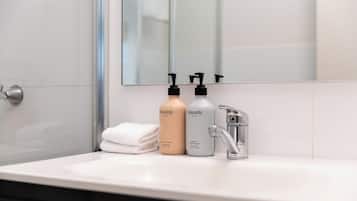 A bathroom with a white sink, two bottles of Sincerely body wash, a towel, and a mirror.
