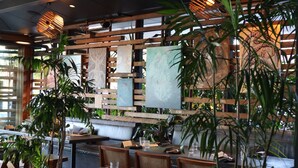 L’intérieur d’un restaurant est décoré de meubles en bois, de plantes en pot et d’œuvres d’art accrochées aux murs.
