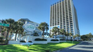 A tall hotel with a modern design, featuring a prominent sign and well-maintained landscaping.