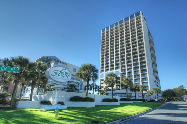 A tall hotel with a modern design, featuring a prominent sign and well-maintained landscaping.