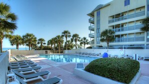 A pool area with lounge chairs and palm trees.