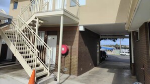 Un bâtiment à deux étages doté d’un espace de stationnement couvert et d’une borne d’incendie fixée au mur.