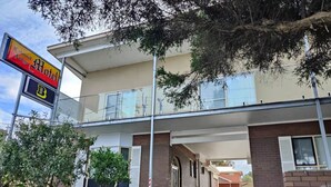 Un motel de style colonial à deux étages, doté d’une galerie couverte et d’un espace de stationnement.
