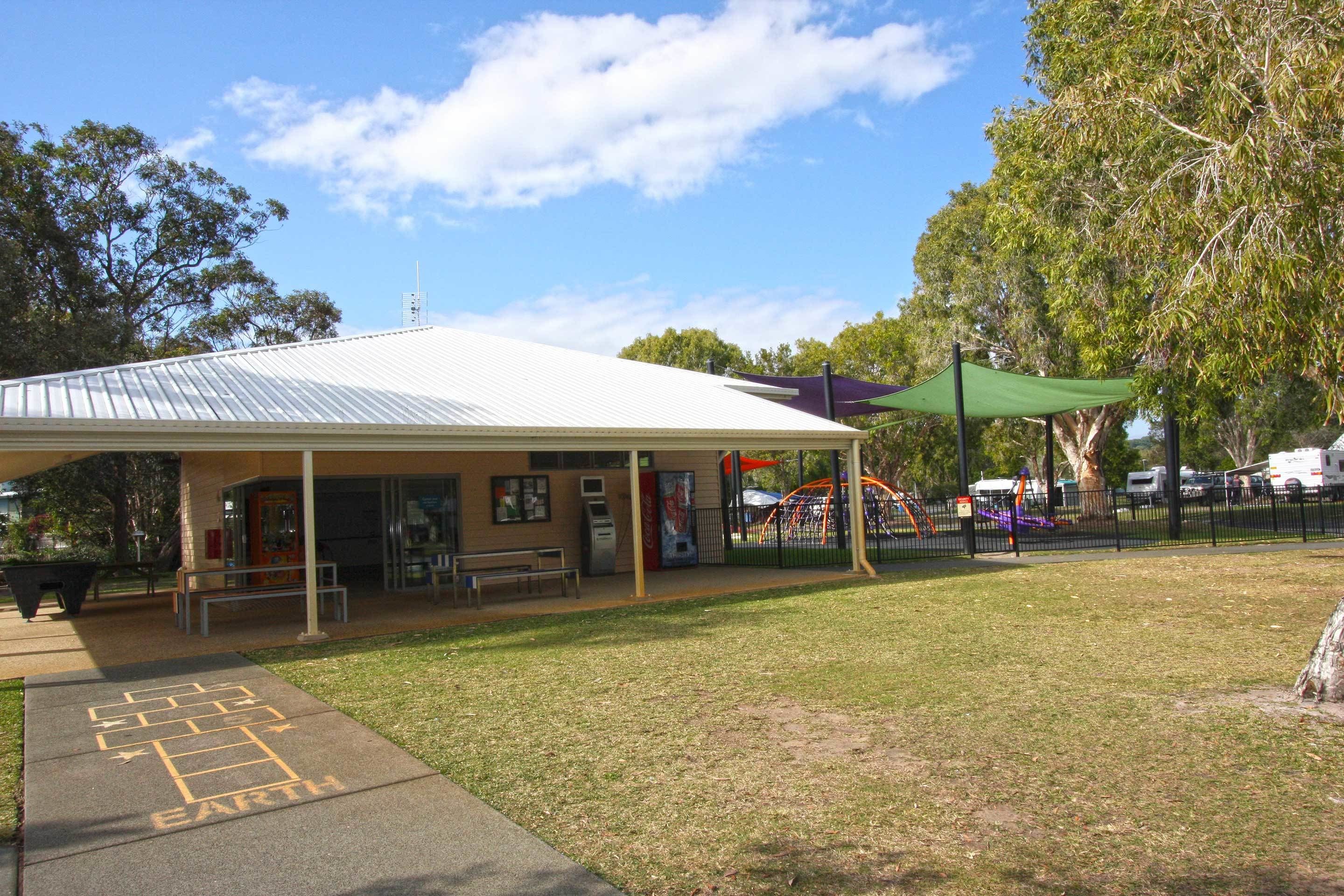 A covered outdoor area with a playground, benches, and a vending machine.