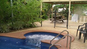 A swimming pool with a metal ladder, surrounded by a brick walkway and greenery. - Charters Towers Tourist Park (Mosman Park)