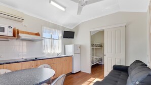 A compact kitchen with a dining area, a sofa, and a bunk bed. - Charters Towers Tourist Park (Mosman Park)