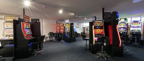 A gaming area with multiple arcade machines, chairs, and a patterned floor.