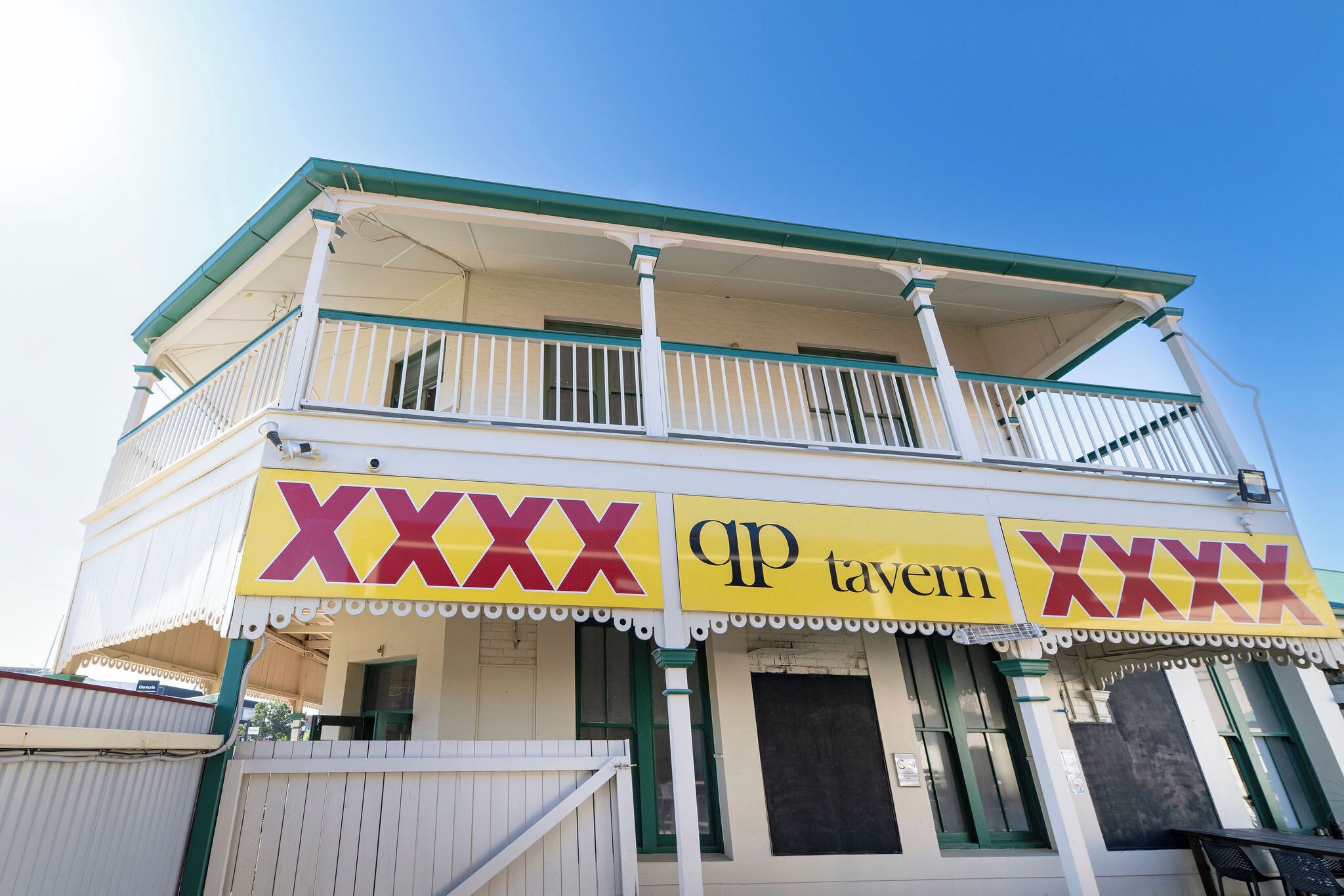 A two-story building with a balcony and a sign that reads 'XXXX tavern'.