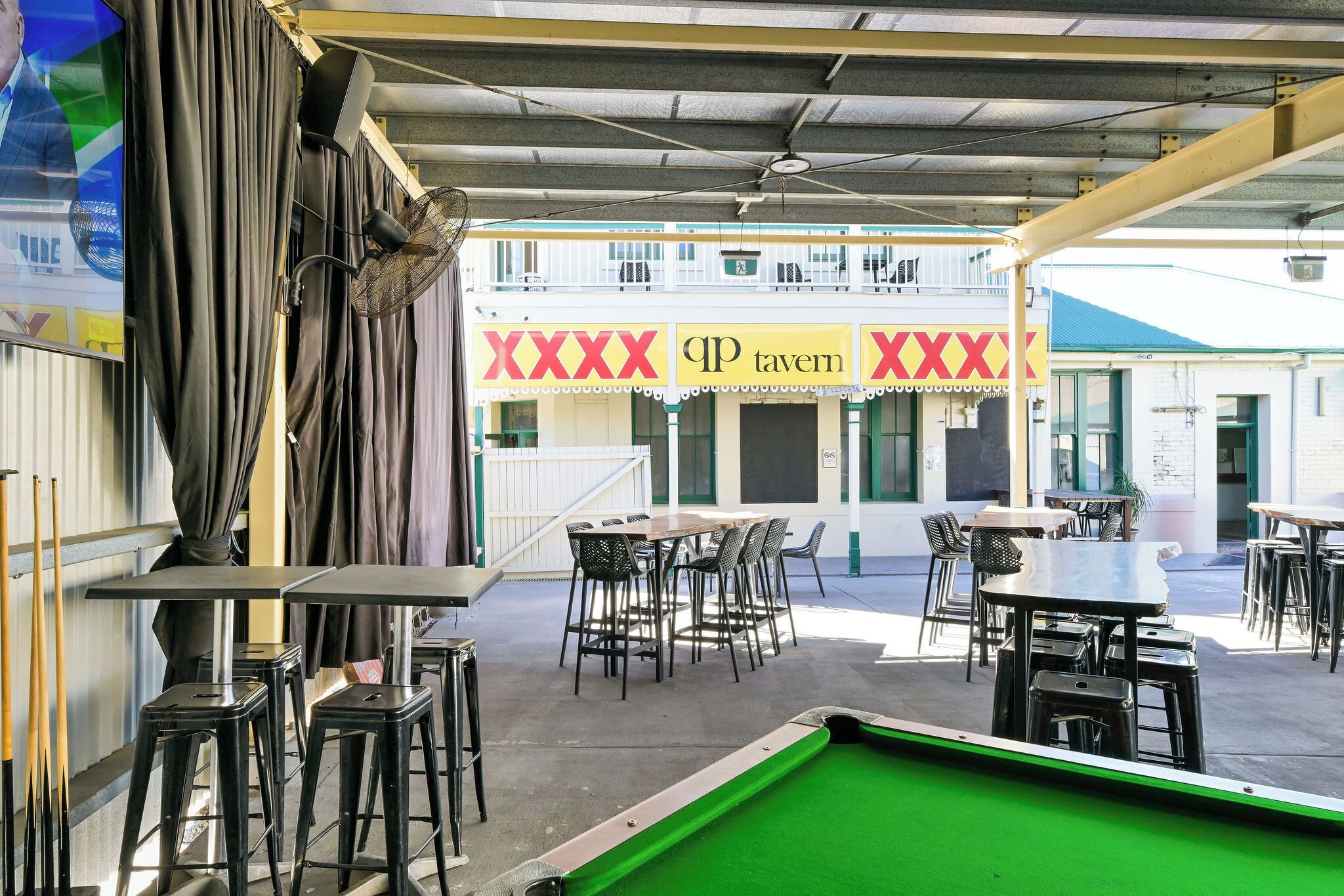 Un espace extérieur aménagé pour les repas, avec des tables et des chaises, un billard et un bâtiment doté d’une enseigne.
