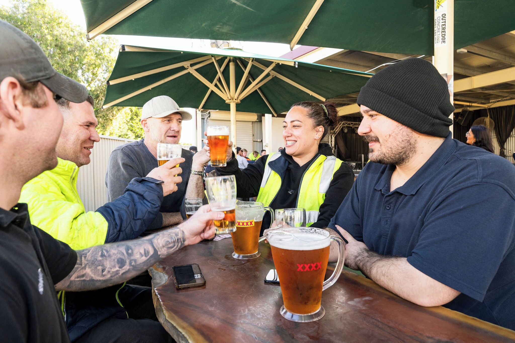 Un grup de persones brindant amb gots de cervesa en un esdeveniment a l'aire lliure.