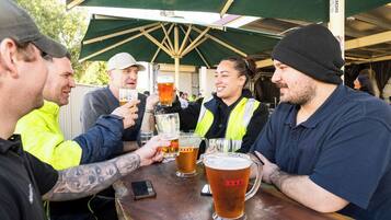 A group of people toasting with beer glasses at an outdoor event.