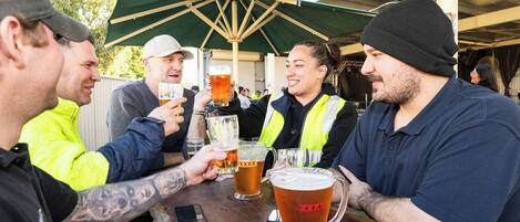 A group of people toasting with beer glasses at an outdoor event.