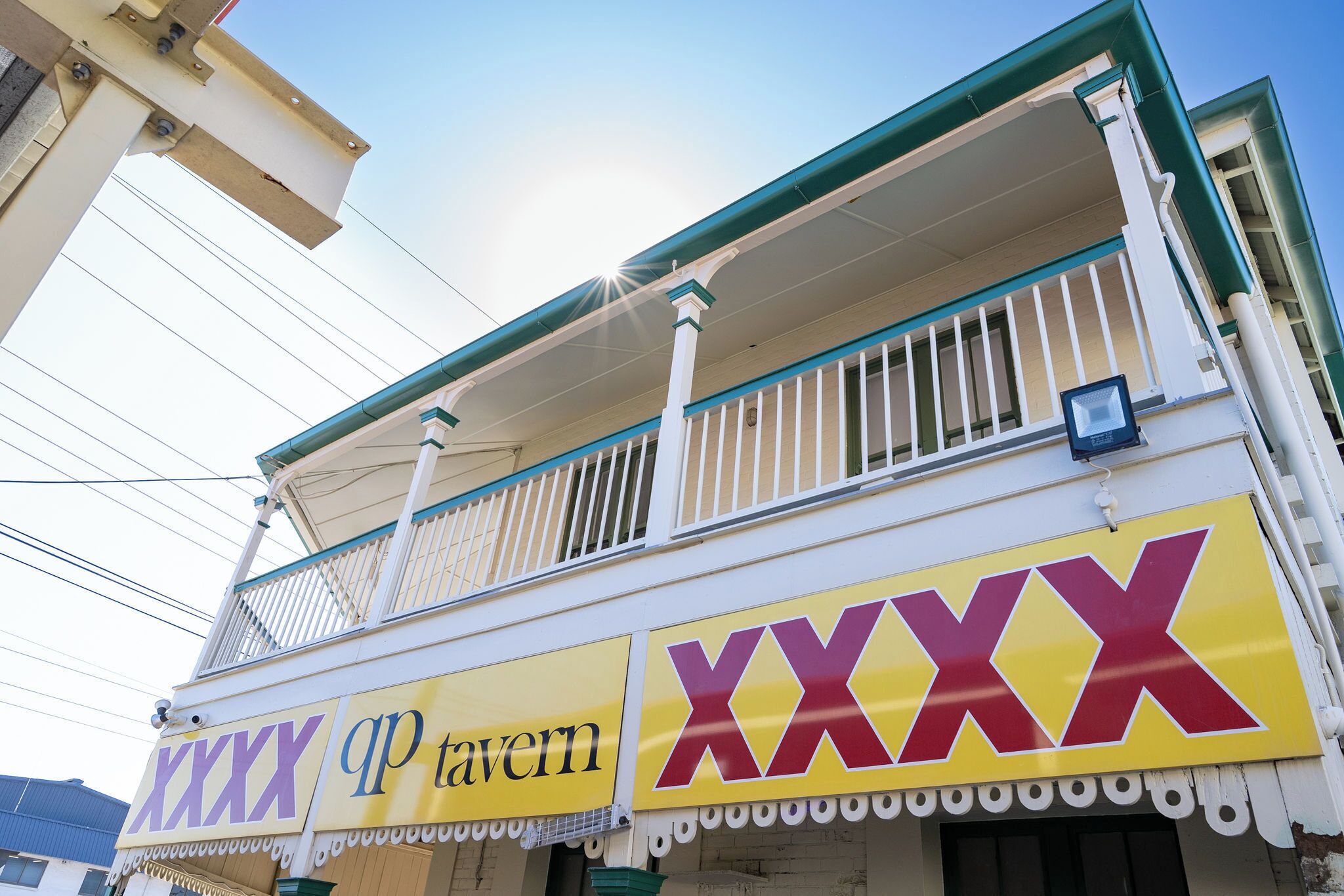 Un edificio con balcón y un letrero que dice 'XXXX tavern'.