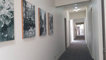 A hallway with three black and white photographs on the wall, carpeted floors, and doors leading to other areas.