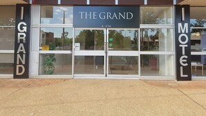A motel entrance with a sign reading "THE GRAND 4-454".