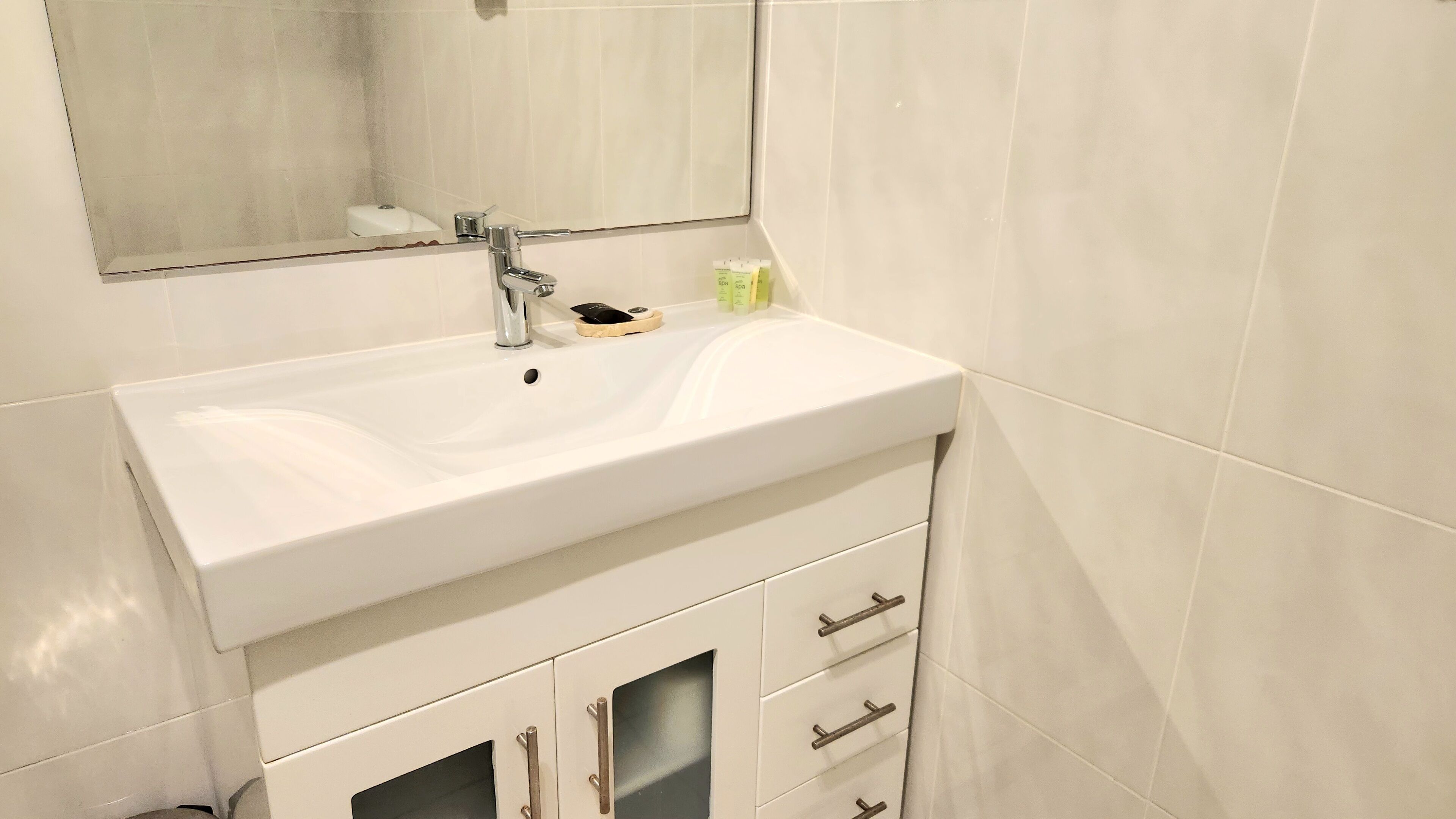 A bathroom with a white sink, a mirror, and a cabinet with drawers.
