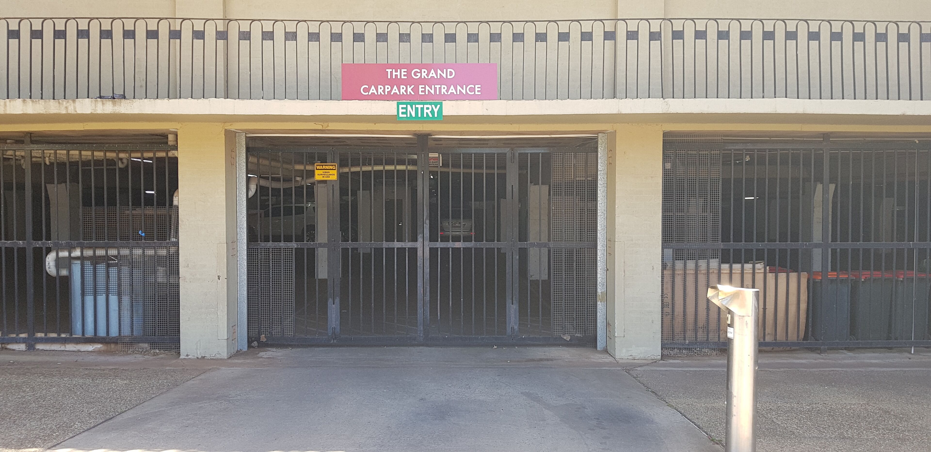 The Grand Carpark Entrance with a metal gate and a warning sign.