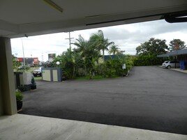 Un estacionamiento con entrada porticada, palmeras y un edificio de techo azul.