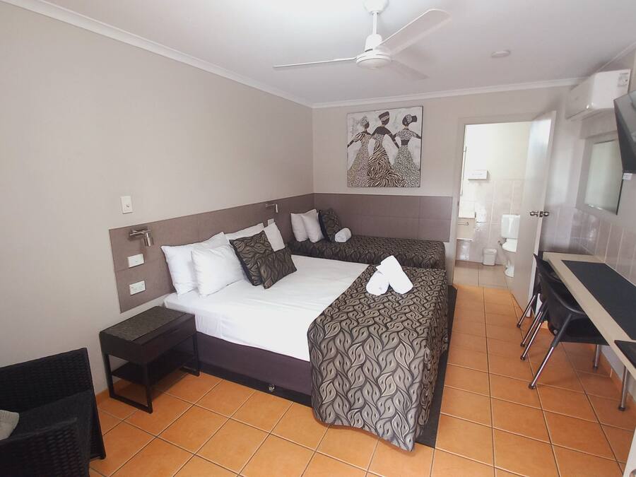 A hotel room with a bed, bedside tables, a desk, a chair, a television, and a bathroom.