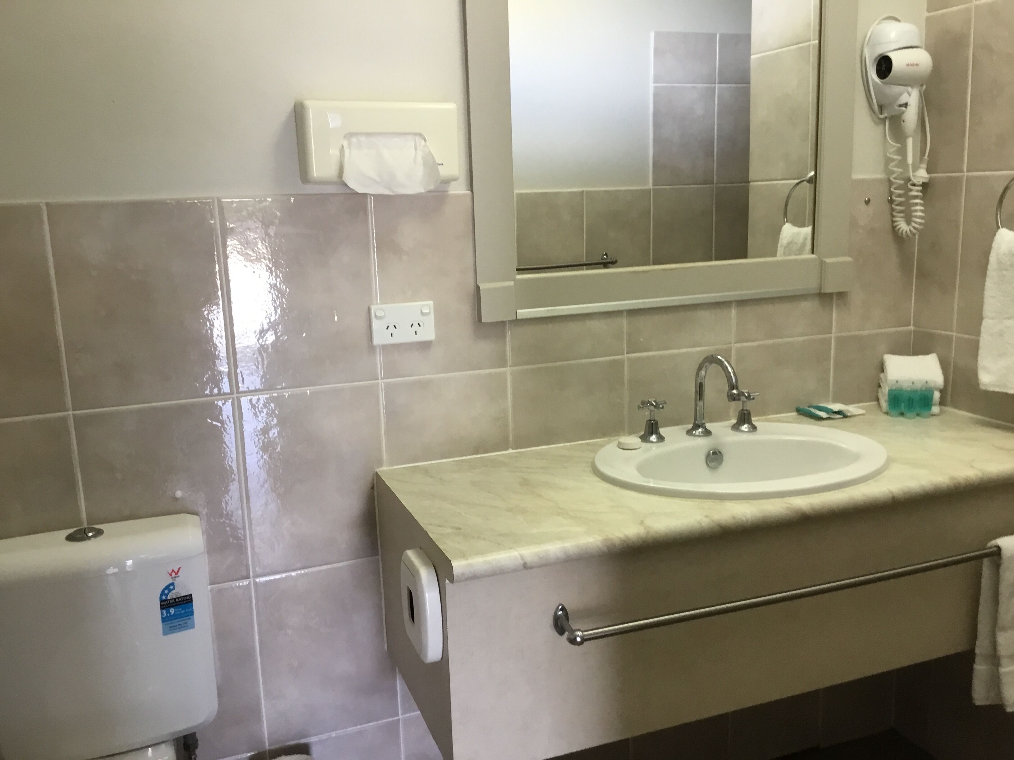 A bathroom with a sink, mirror, hair dryer, and hand dryer.