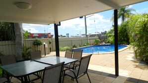 A covered patio with a pool, outdoor seating, and a view of the surrounding area. - Golden Palms Motor Inn (Bundaberg)