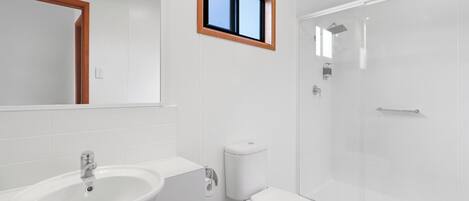 Un baño con lavamanos, inodoro y cabina de ducha de vidrio.
