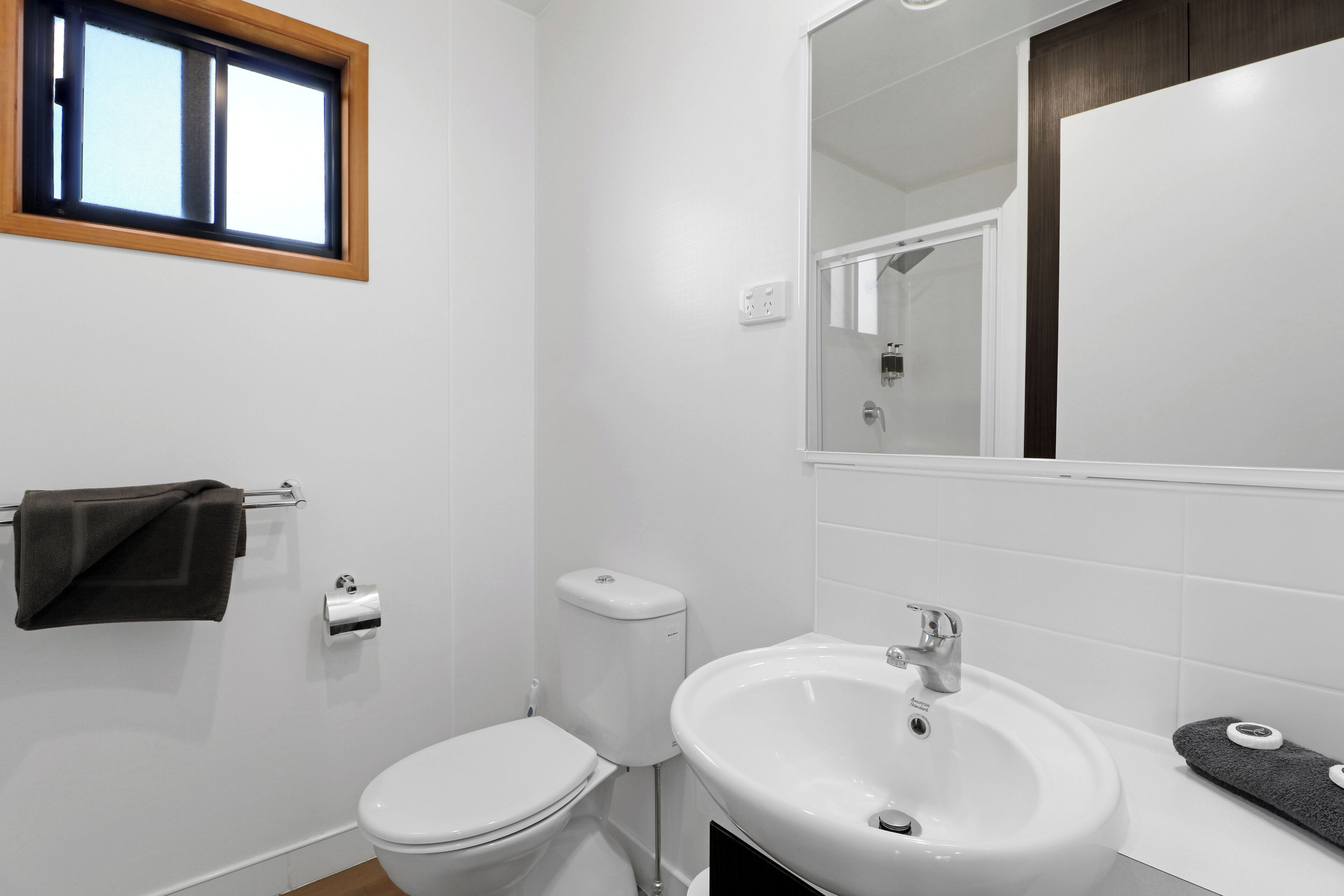A bathroom with a toilet, sink, and a window.