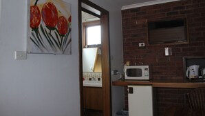 A compact kitchen with a microwave, a small refrigerator, and a wooden countertop. - Kardinia Park Motel (Newtown)