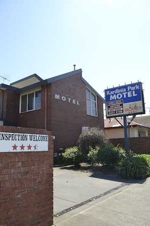 Edificio de ladrillo con un letrero que dice "Kardinia Park Motel" y otro que indica "Habitación disponible".