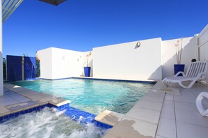 Een buitenzwembad, parasols bij het zwembad en ligstoelen